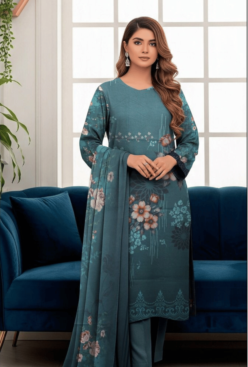 Woman in a teal floral dress standing in a room with a blue couch and white walls.