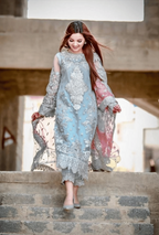 Woman in a light blue and gray embroidered dress walking up stone steps.
