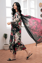 Woman in a floral dress holding a black dupatta with pink roses in a bright room.