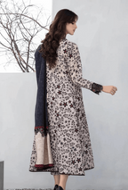 Woman wearing a floral dress with a scarf, standing against a white wall.