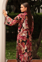 Woman wearing a floral dress standing outdoors with greenery in the background