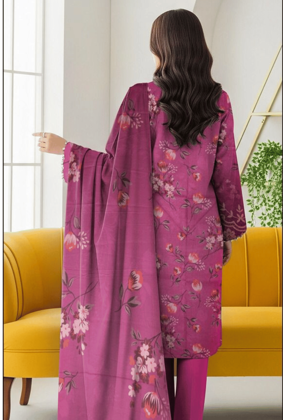 Woman wearing a pink floral outfit in a room with a yellow couch and white walls.