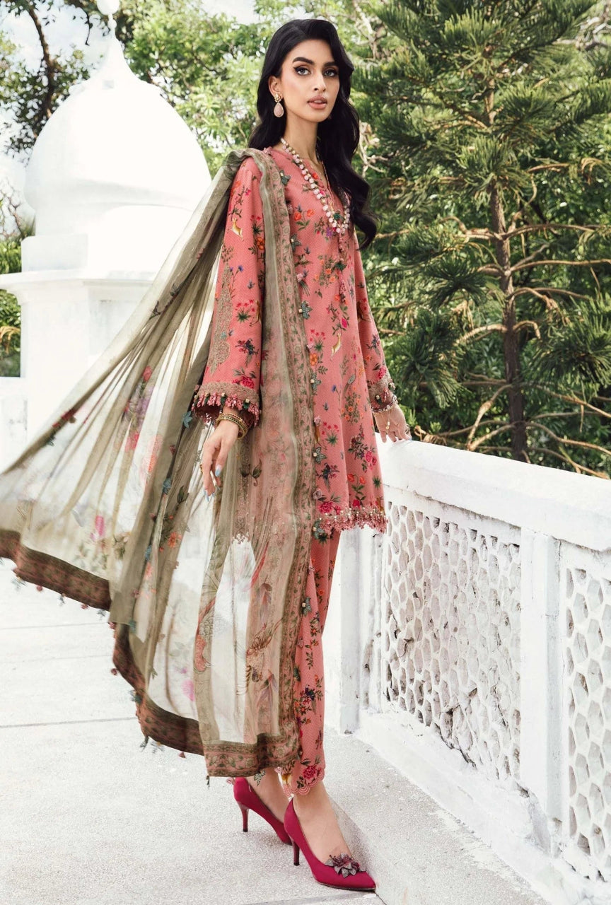 Woman in traditional pink and beige outfit with floral patterns, standing outdoors.