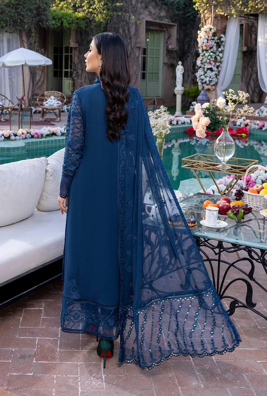 Woman in a blue traditional outfit standing by a poolside with decorative elements.