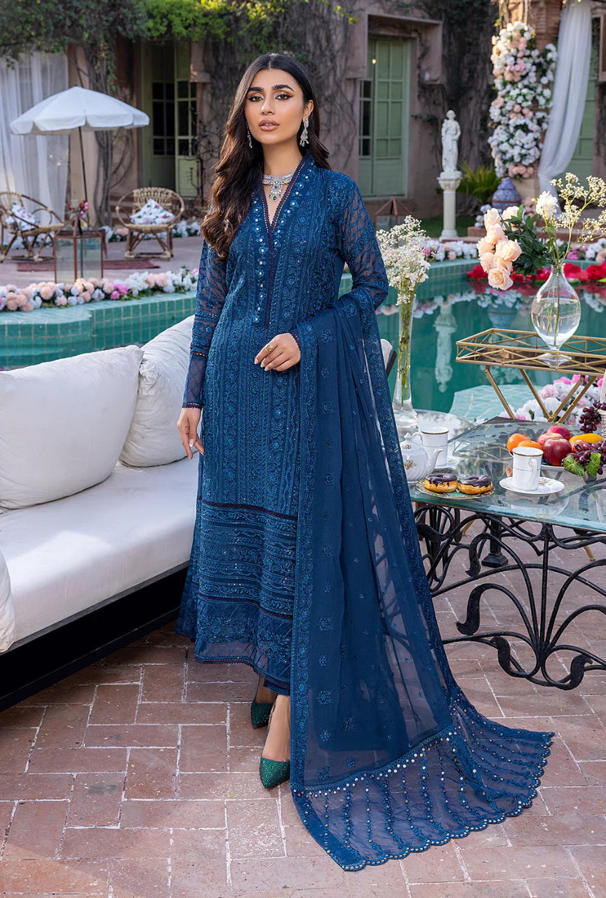 Woman in a blue traditional outfit standing by a poolside with decorative elements.
