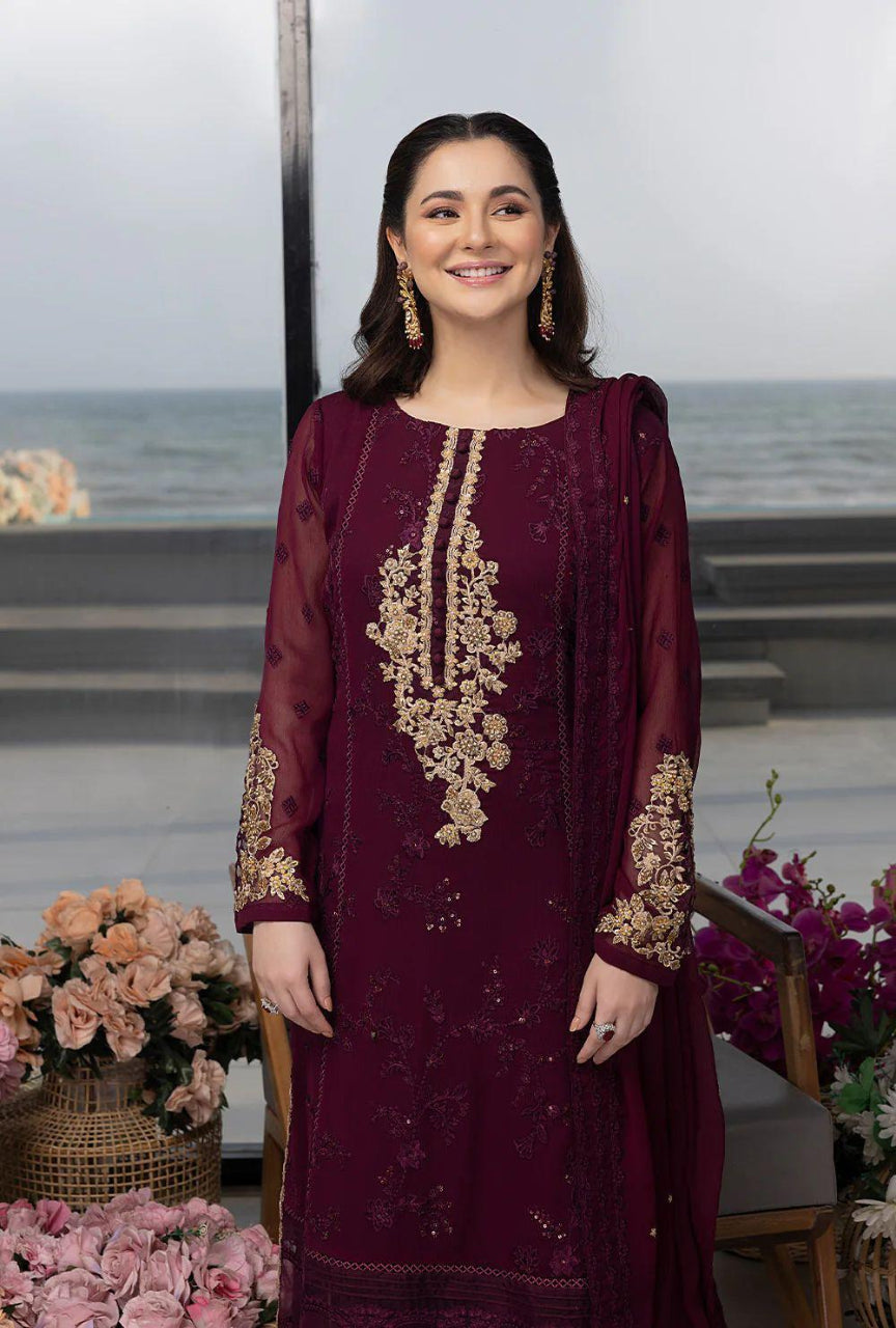 Woman in a burgundy embroidered dress with floral arrangements and a blurred background