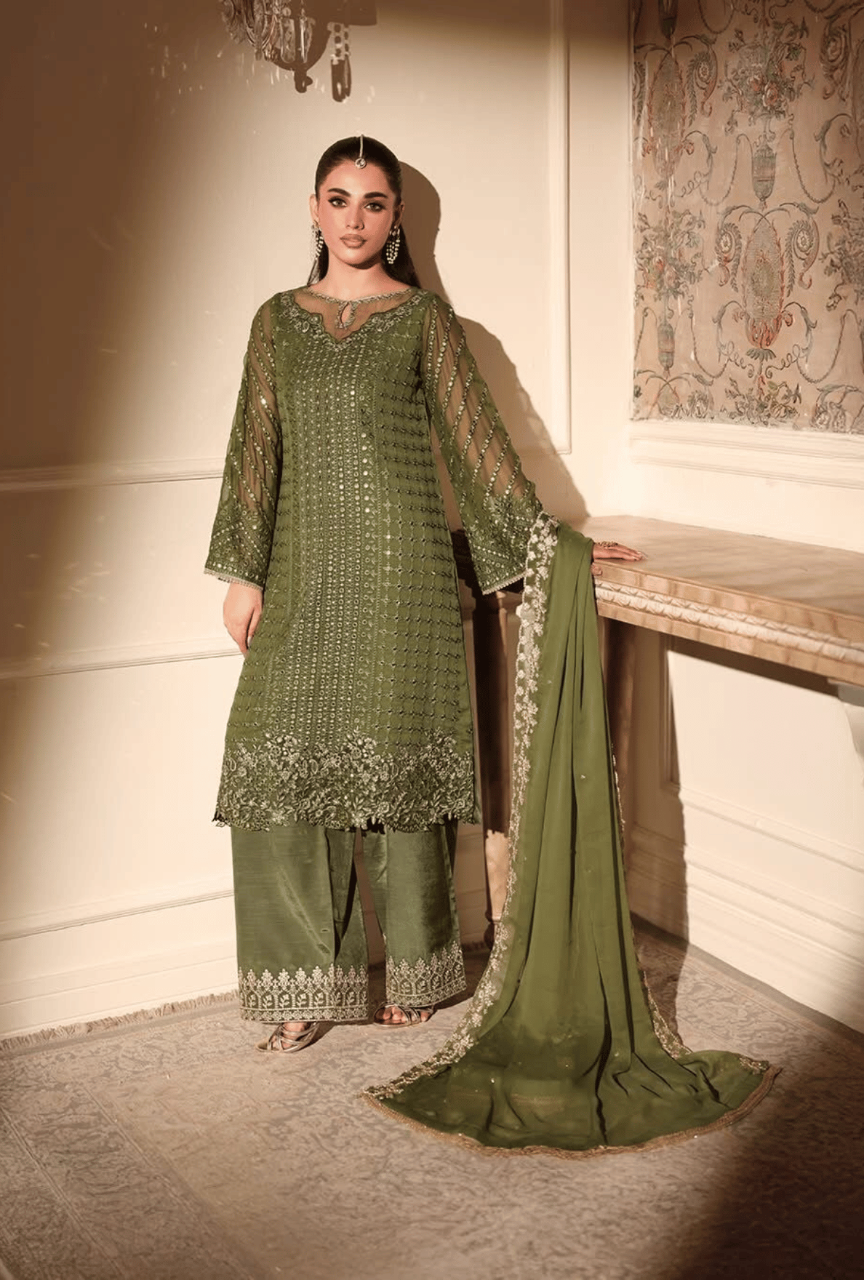 Woman wearing a green traditional outfit with a matching dupatta in a decorated room.