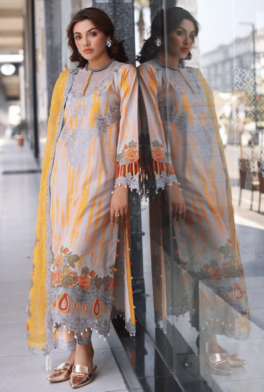 Woman wearing a traditional outfit with a yellow and gray patterned dress in a reflective setting.