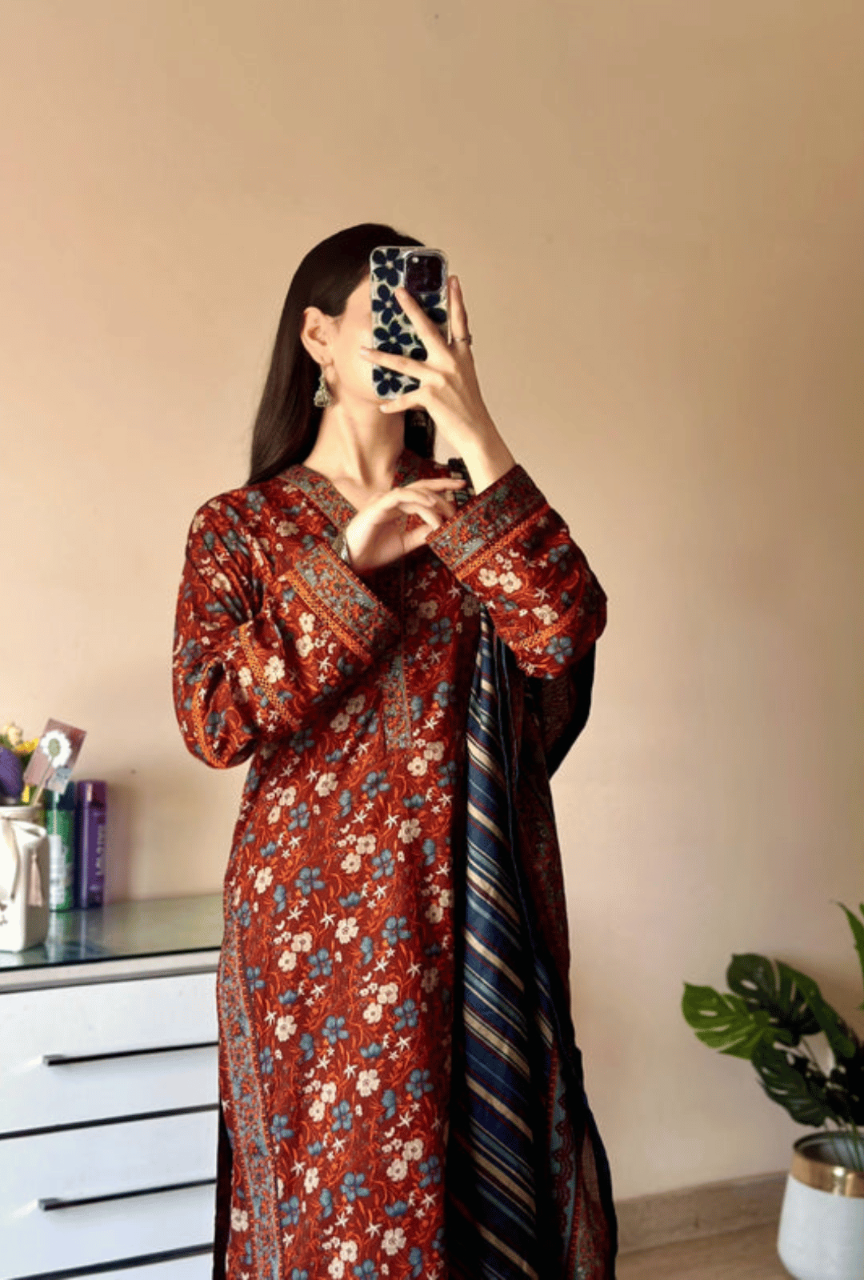 Woman taking a mirror selfie wearing a floral dress with a striped scarf.