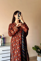 Woman taking a mirror selfie wearing a floral dress with a striped scarf.
