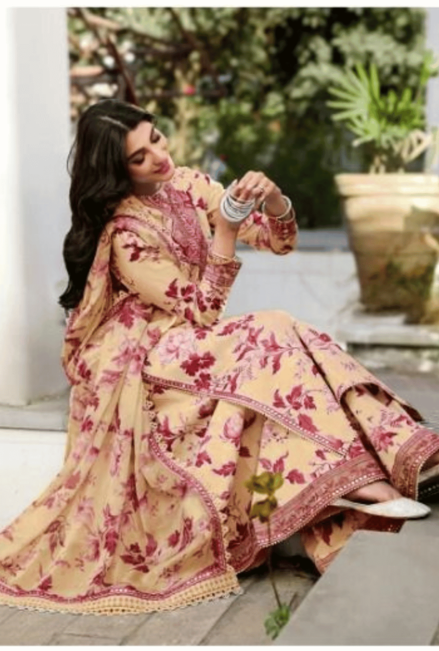 Woman in a floral saree sitting outdoors with plants in the background