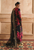 Woman wearing a black saree with red floral patterns in an elegant indoor setting.