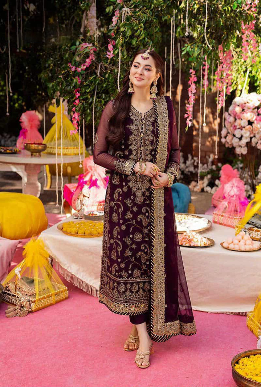 Woman in traditional attire standing in a decorated indoor setting with floral arrangements and festive decorations.