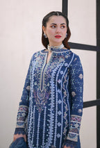 Woman wearing a blue embroidered dress against a neutral background