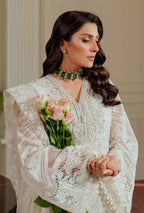 Woman in a white lace outfit holding pink roses indoors