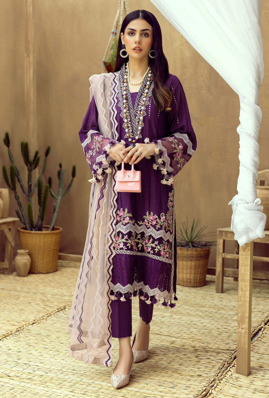 Woman in a purple traditional outfit with floral patterns in an indoor setting.