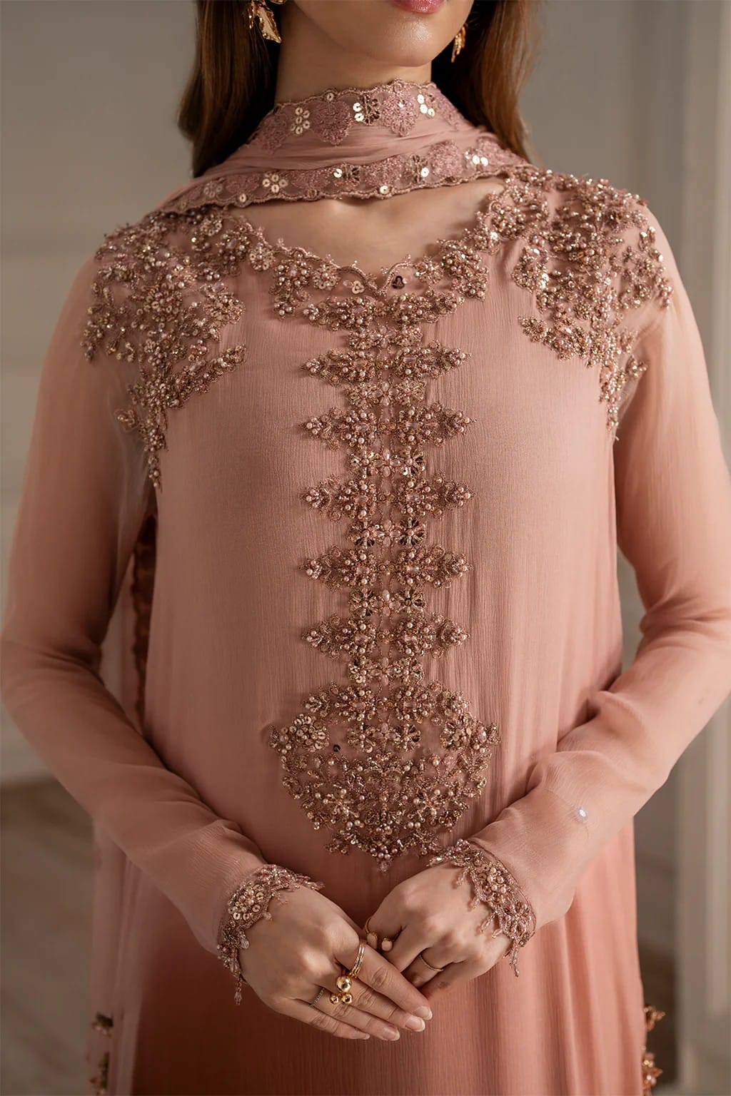 Pink embroidered dress with intricate detailing on a neutral background