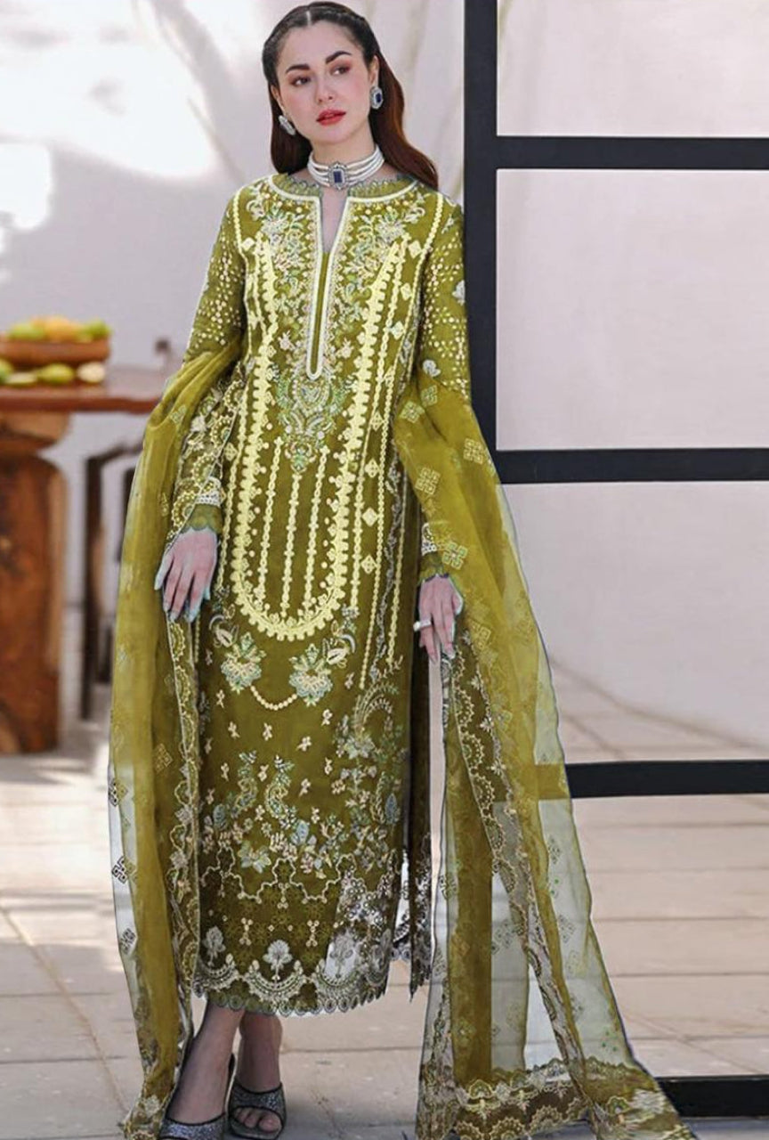 Woman wearing a green embroidered traditional outfit with a sheer dupatta.