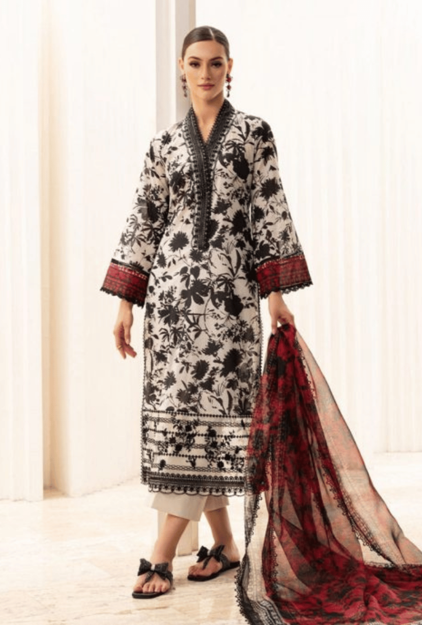Woman wearing a black and white floral dress with a red and black dupatta, standing against a white background.