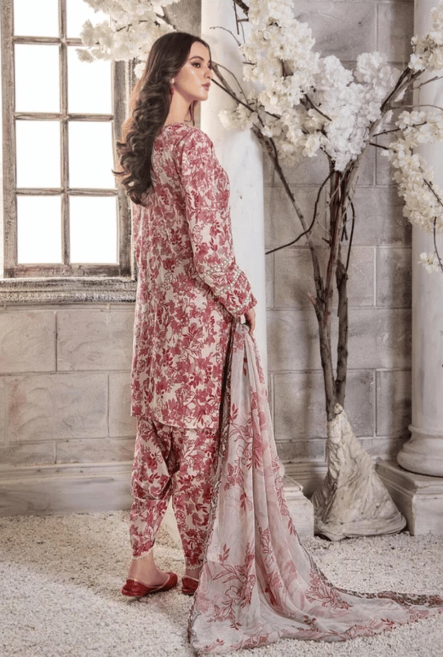 Woman in a floral outfit standing in a decorated room with white flowers and a window.