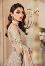 Woman in an elegant outfit with intricate detailing, standing in a softly blurred indoor setting.