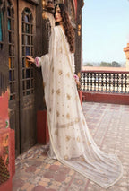 Woman in a white embroidered saree standing on a balcony with a scenic background