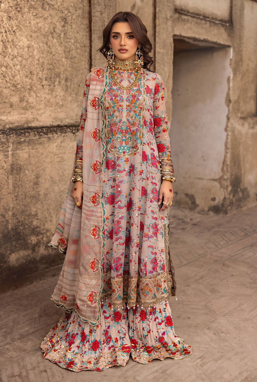 Woman in a floral dress with a matching dupatta standing against a textured wall.