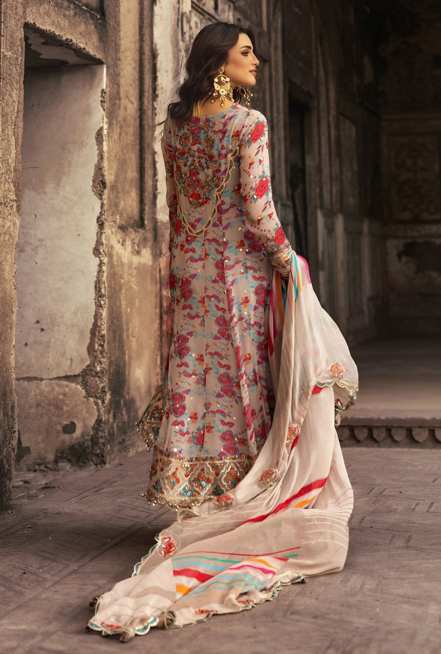 Woman in a floral dress with a white dupatta standing in an architectural setting.