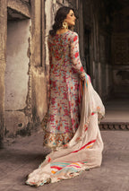 Woman in a floral dress with a white dupatta standing in an architectural setting.