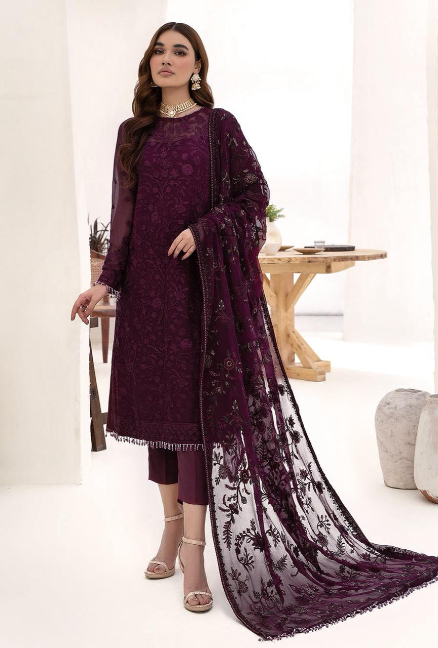 Woman wearing a purple embroidered outfit with a matching dupatta in a minimalistic setting.