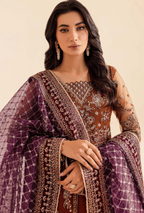 Woman wearing a traditional outfit with intricate patterns and jewelry against a beige background