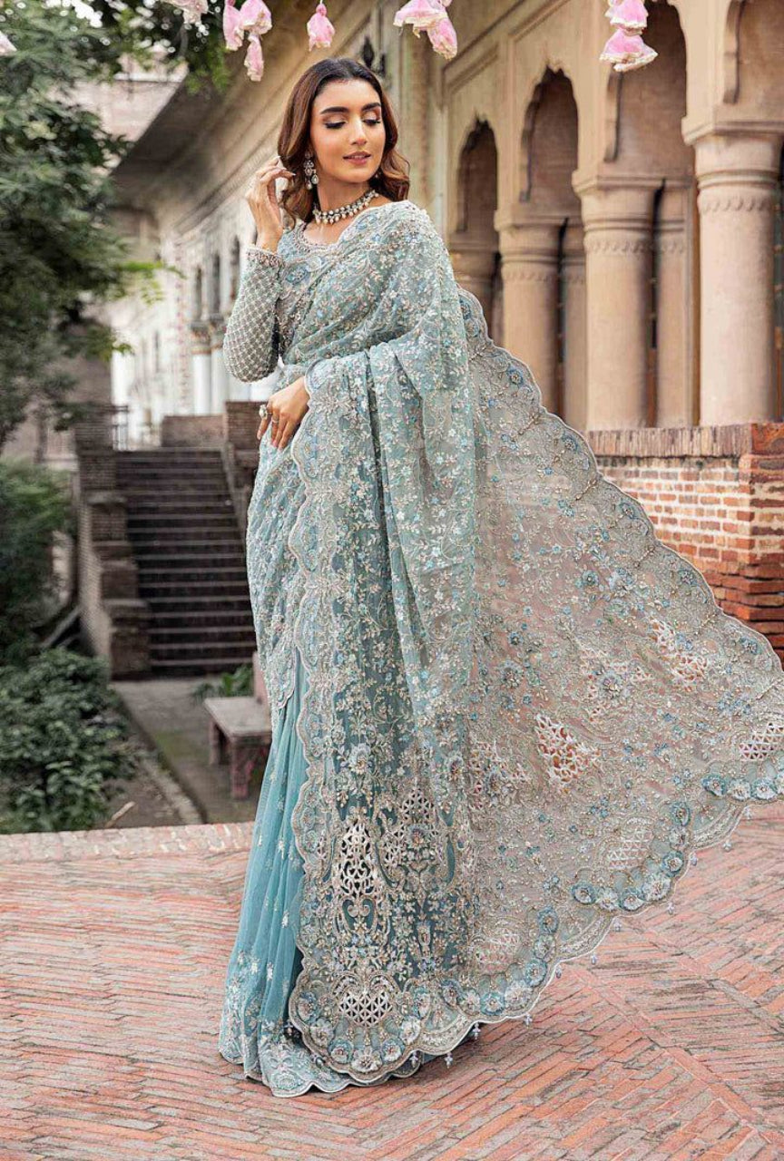 Woman in a light blue saree with floral decorations outdoors.