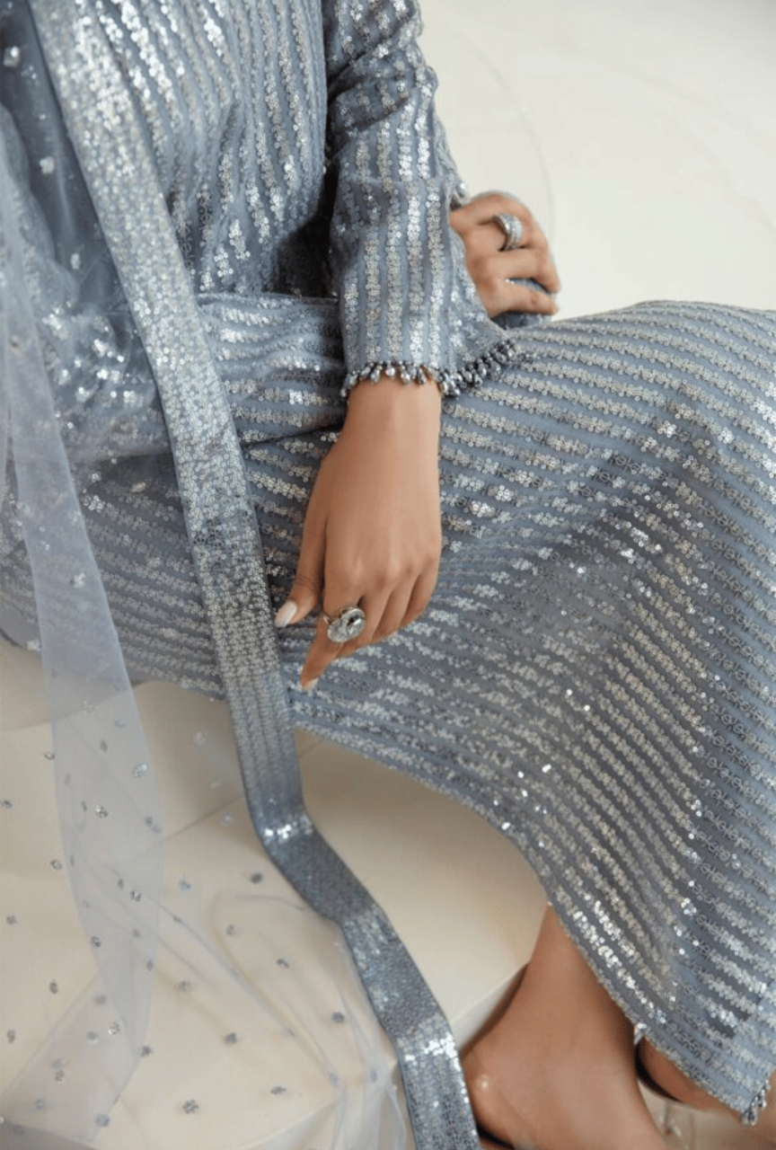Person wearing a silver sequin outfit sitting on a white surface