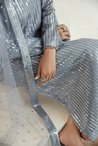 Person wearing a silver sequin outfit sitting on a white surface