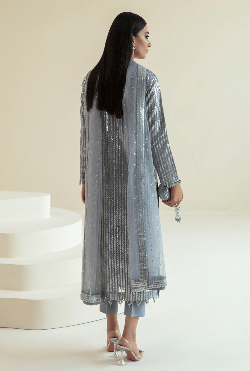 Woman wearing a long, patterned dress standing in a minimalistic setting.