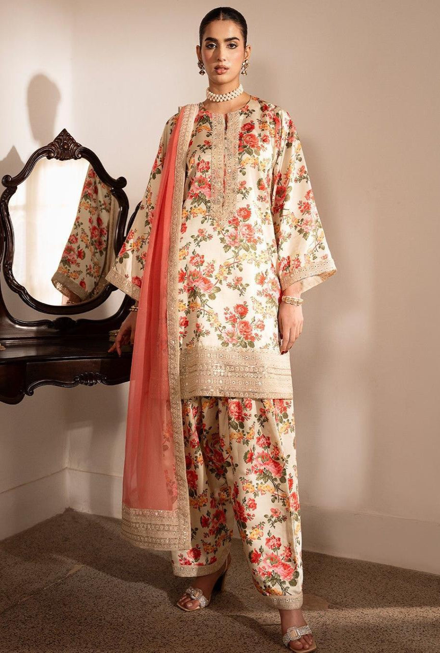 Woman wearing a floral traditional outfit with a pink dupatta in a room setting.