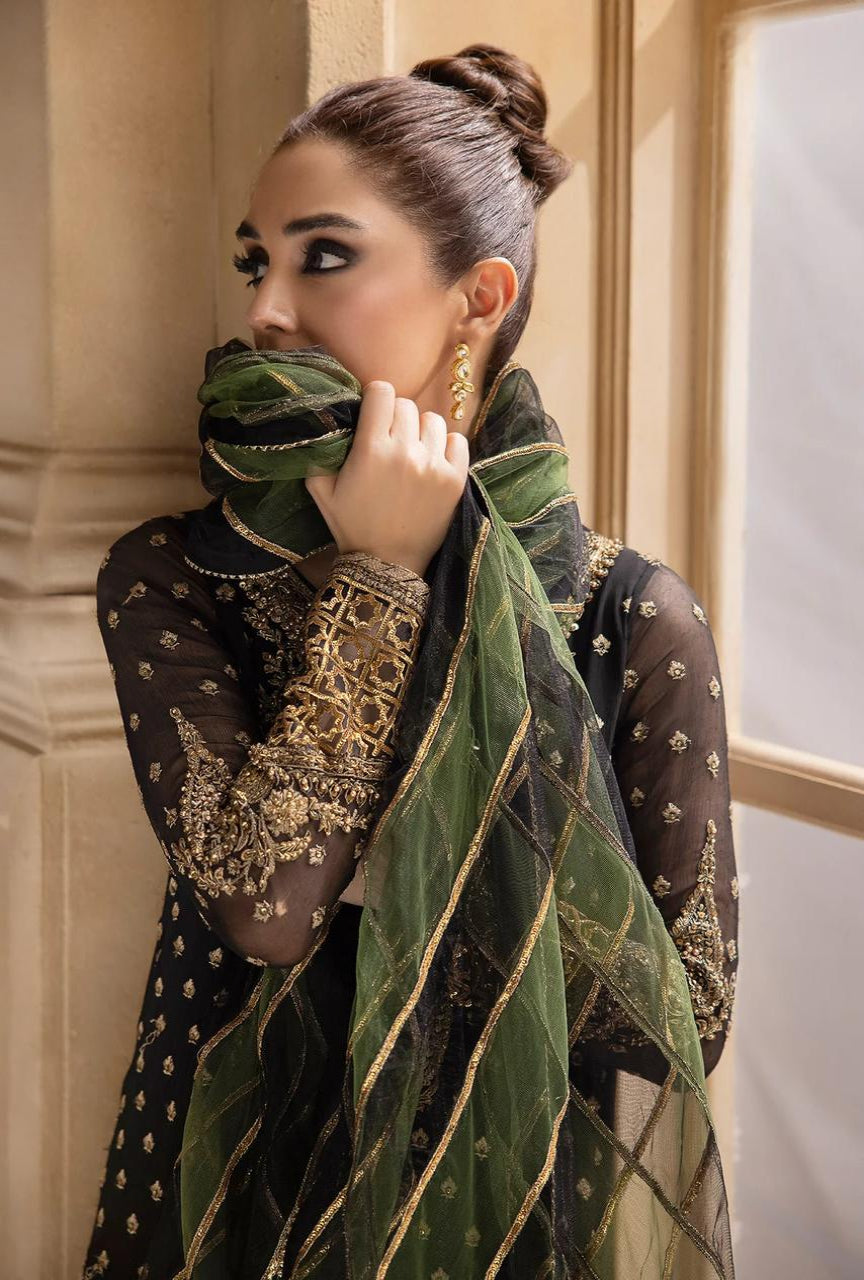 Woman wearing a green and gold embroidered dupatta in an indoor setting