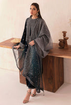 Woman in a black and gray traditional outfit standing next to a wooden table.