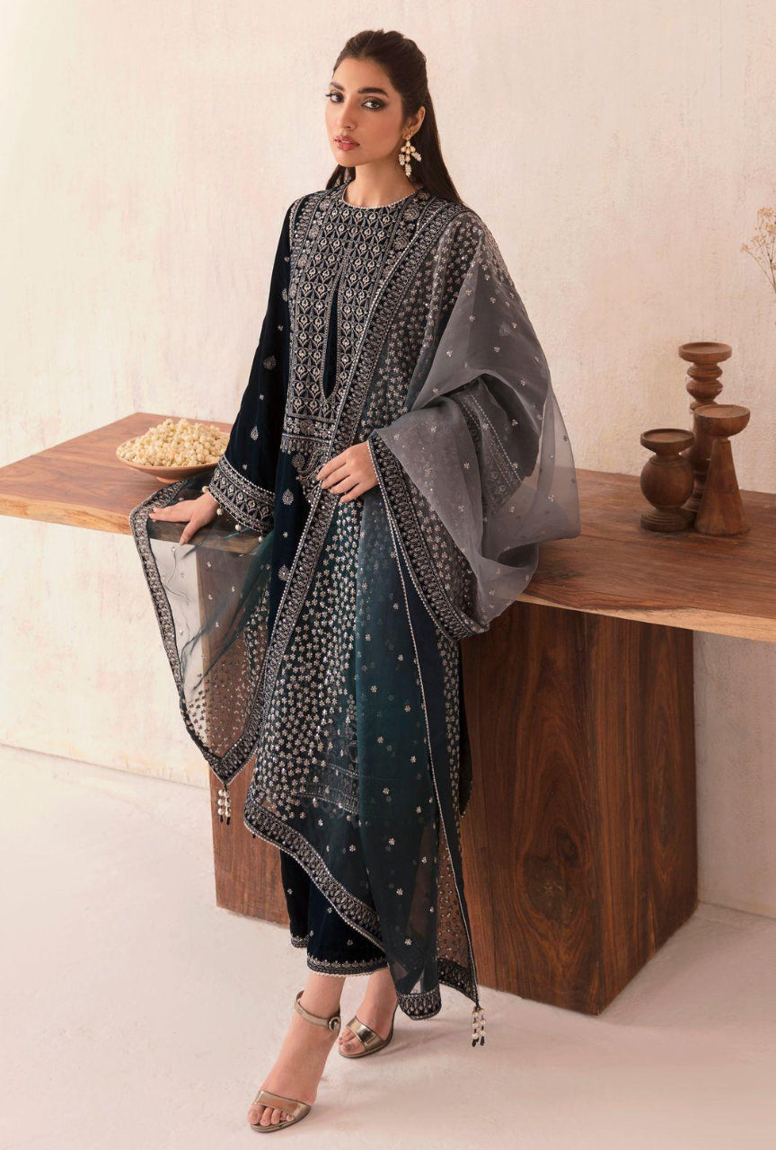 Woman in a black and gray traditional outfit standing next to a wooden table.