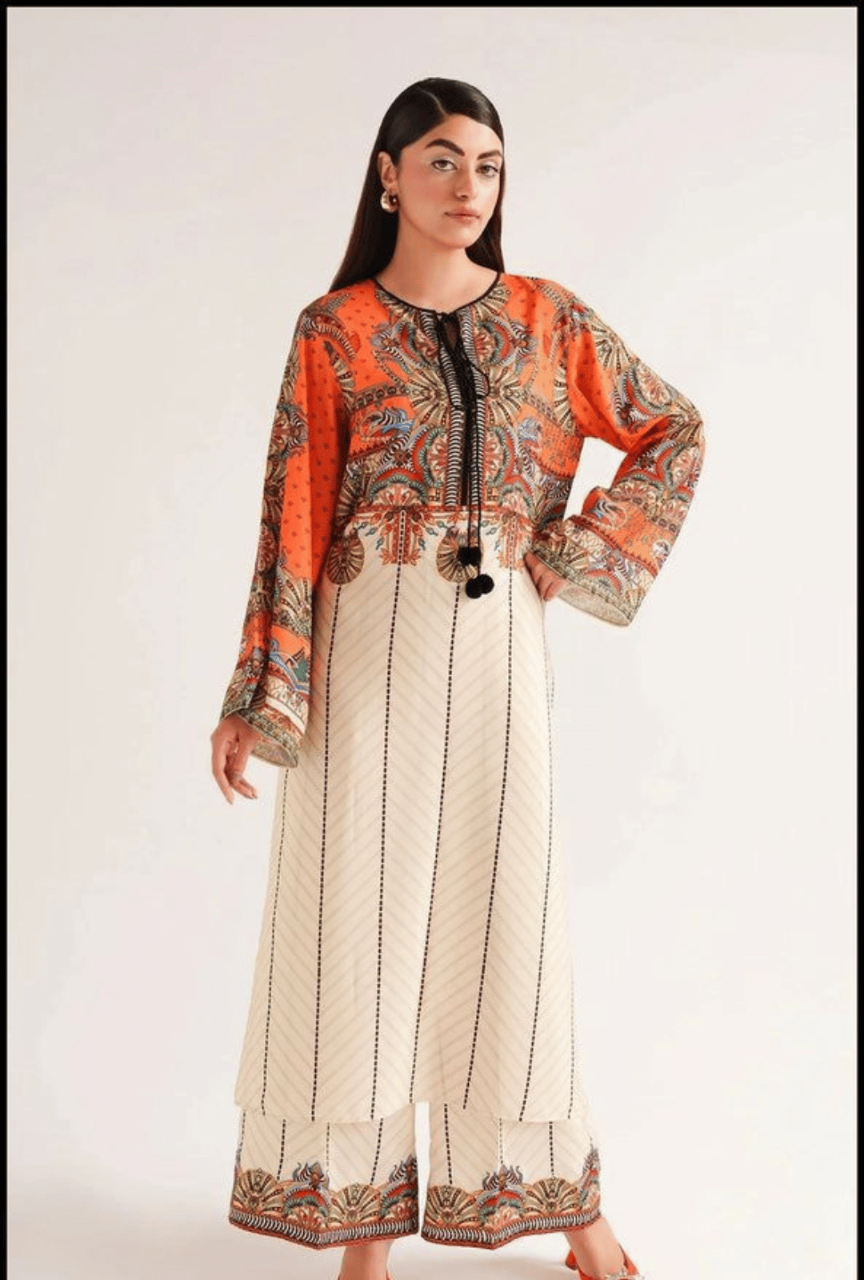 Woman wearing a patterned top and white pants with black stripes on a plain background