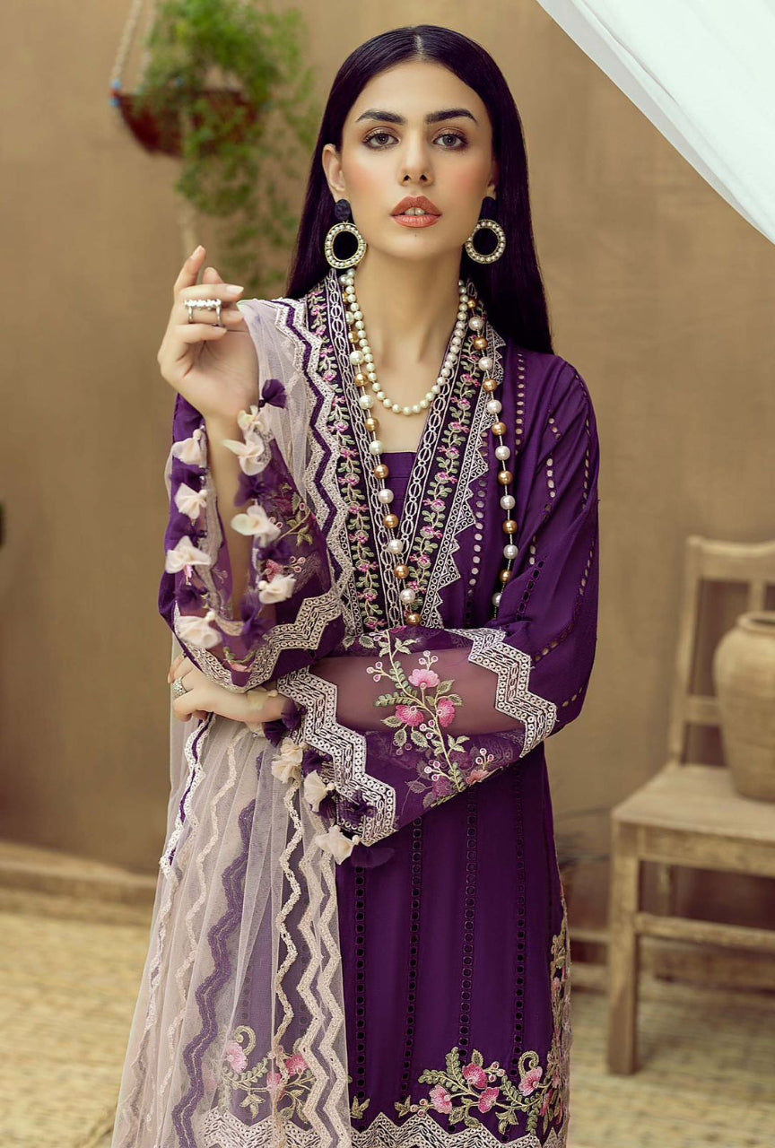 Woman in a purple embroidered outfit with jewelry indoors.