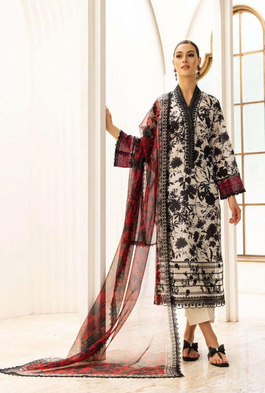 Woman wearing a black and white floral dress with a red and black dupatta in a bright room.