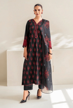 Woman wearing a black and red floral dress with a sheer dupatta in a minimalistic setting