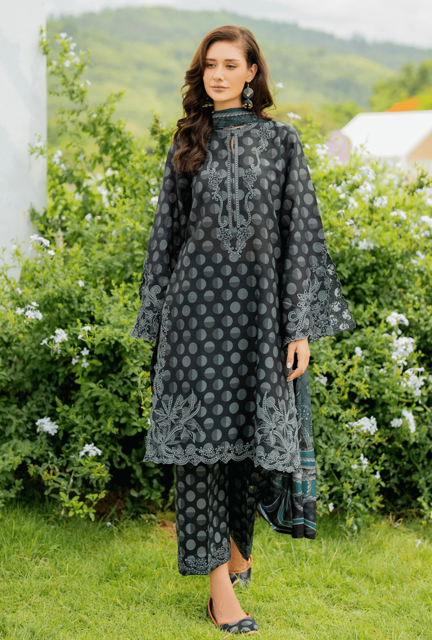 Woman wearing a dark gray embroidered traditional outfit in a garden setting