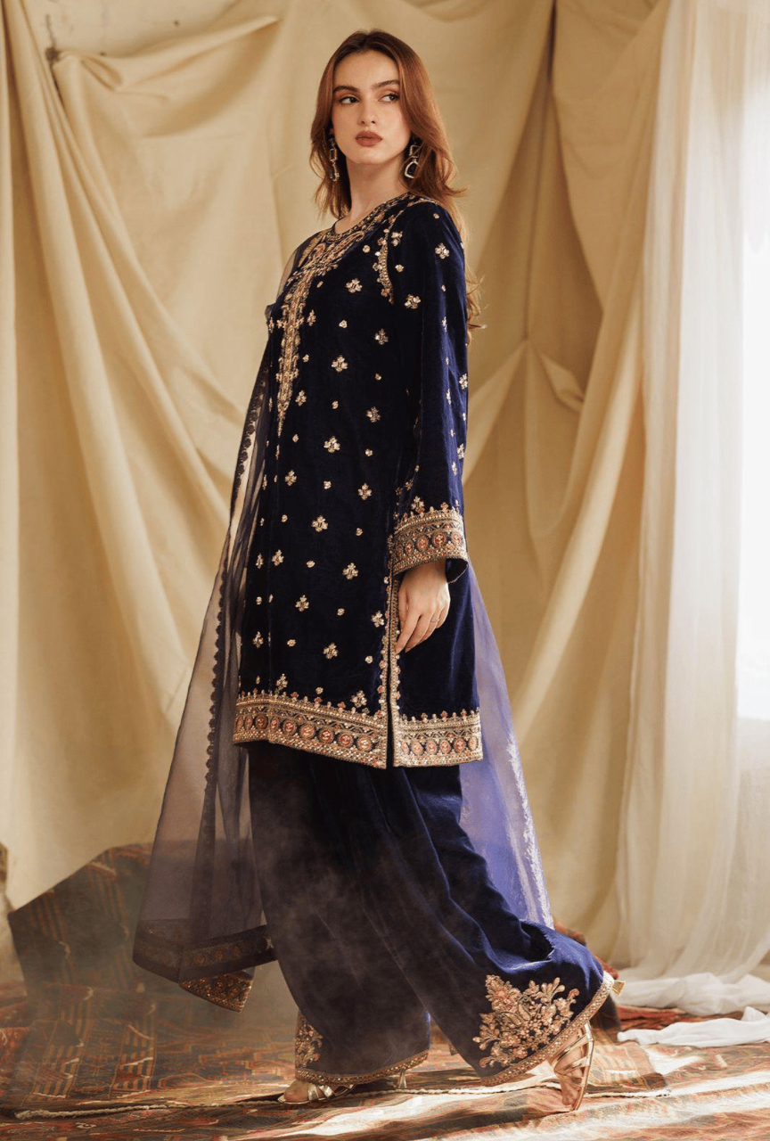 Woman wearing a traditional embroidered outfit with a plain background