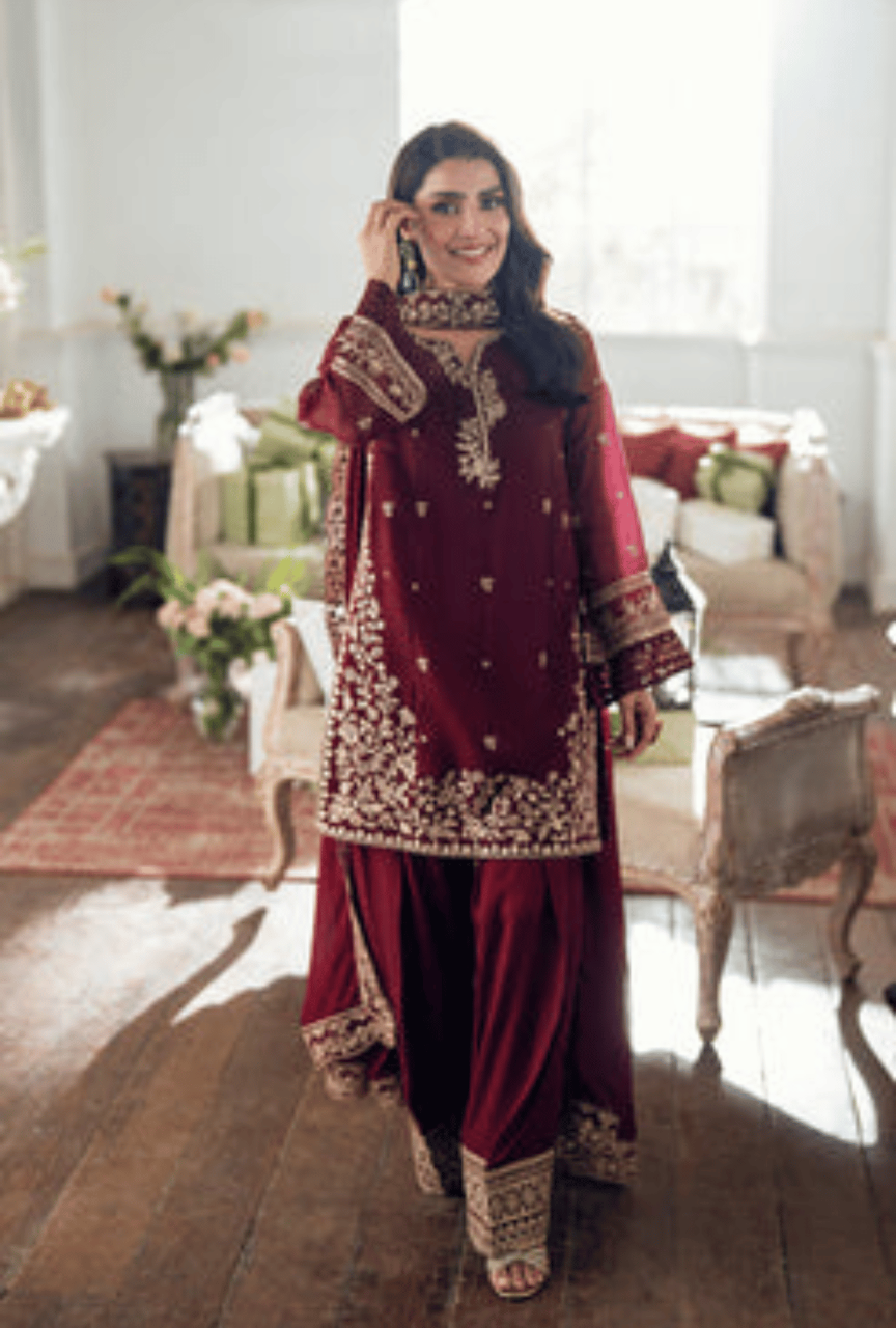 Woman in a red traditional outfit with gold embroidery in a decorated room.
