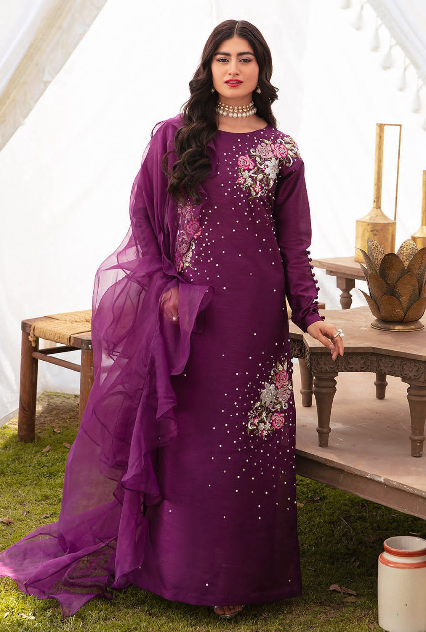 Woman in a purple traditional outfit with floral embroidery standing outdoors.
