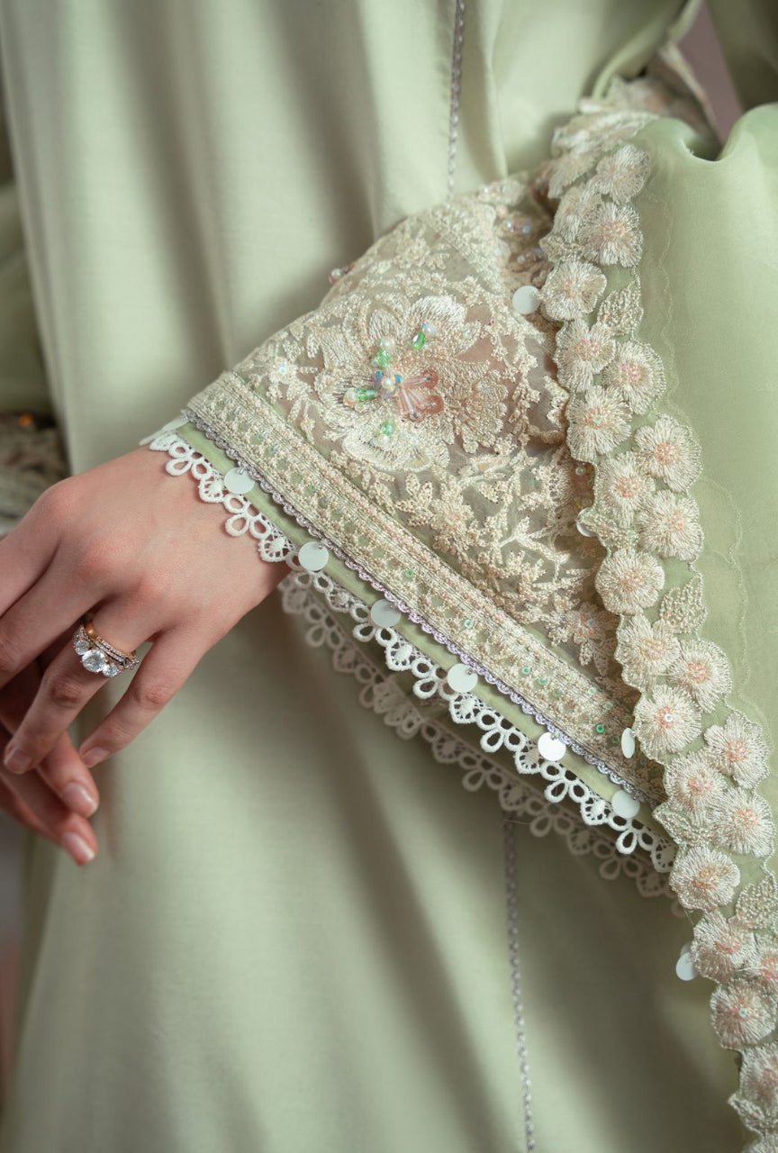 Close-up of a person wearing a light green dress with intricate lace detailing.