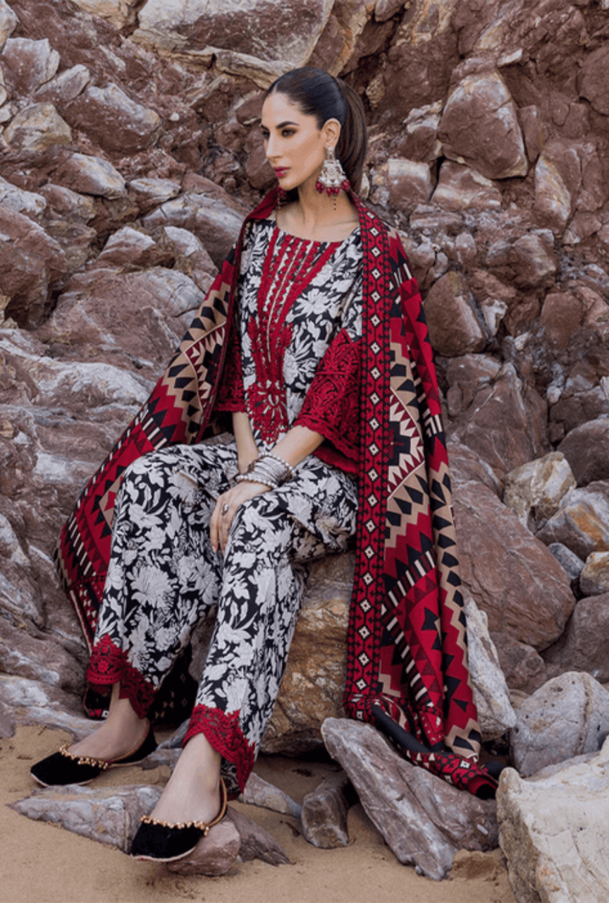 Woman in a patterned outfit sitting on rocks against a stone wall.