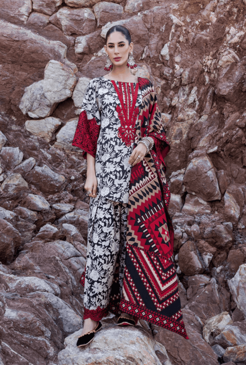 Woman in a patterned outfit standing against a rocky wall